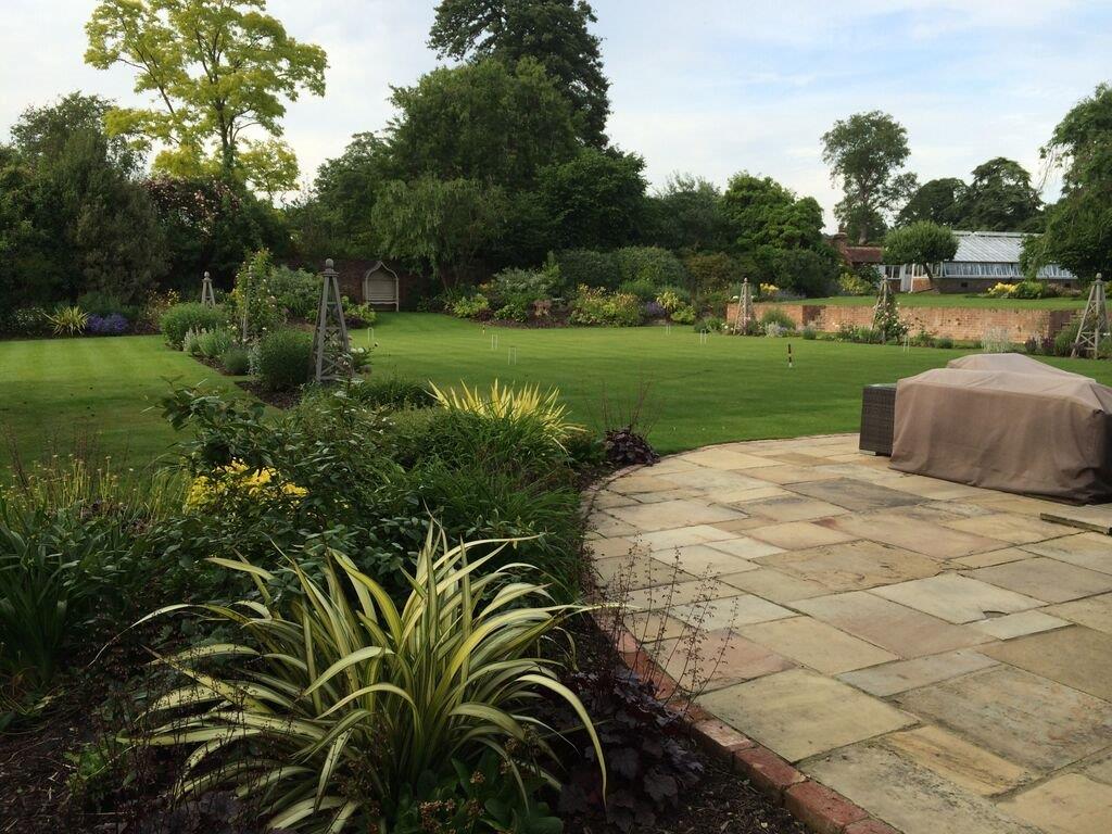 A completed Soil Sisters garden project showing deep planted borders flanking a central lawn